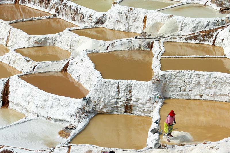 Woman extracting salt from one of the wells of the Maras salt mines