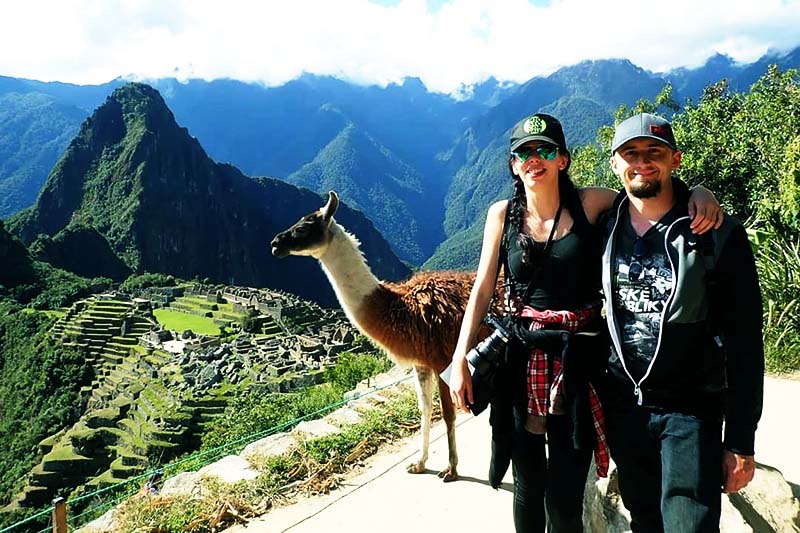 El mejor momento para visitar Machu Picchu Turistas en Machu Picchu junto a una llama