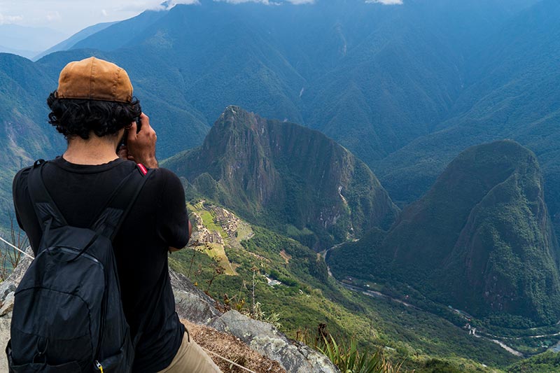 Visitor photographing from the top of Machu Picchu Mountain